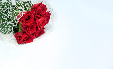 A bouquet of bright red roses lies on a white table.