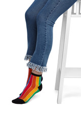 Medium bottom shot of female legs in striped rainbow-coloured socks with black heels, toes and...