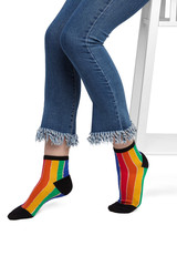 Medium bottom shot of female legs in striped rainbow-coloured socks with black heels, toes and...
