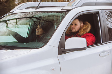 man and woman inside car in winter clothes.