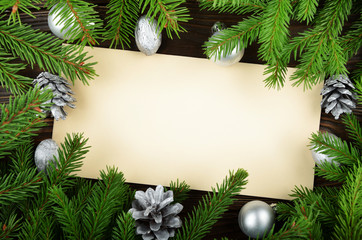 Flat lay mockup of holiday greeting card made of brown craft paper fir twigs cones gingerbread cookies and baubles with copy-space