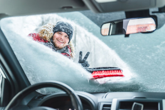 cleaning car after snow storm smiling man with brush