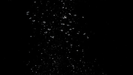 Blurry images of soda water bubbles splashing and floating up to top of water surface which little and big circle texture shaped up by gas power in carbonate drink make refreshing moment on black