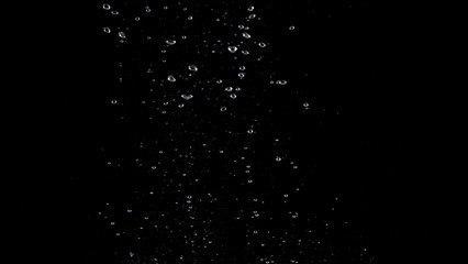 Blurry images of soda water bubbles splashing and floating up to top of water surface which little and big circle texture shaped up by gas power in carbonate drink make refreshing moment on black