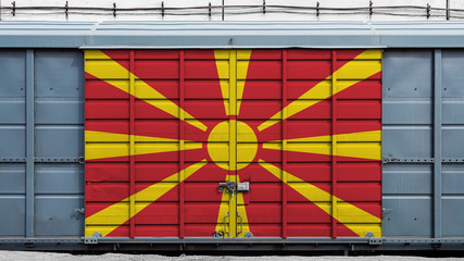 Front view of a container train freight car with a large metal lock with the national flag of Macedonia.The concept of export-import,transportation, national delivery of goods and rail transportation