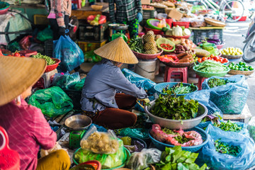 Women selling food on the street of Hoi An, Vietnam - obrazy, fototapety, plakaty