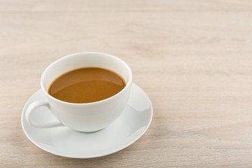 Coffee in a white cup placed on a wooden table