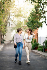 Fototapeta na wymiar Young female couple walking and laughing in the street looking between them