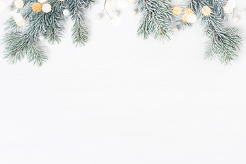 White wooden background decorated wit h frosty fir branches and lights, Christmas of New Year holiday frame - obrazy, fototapety, plakaty