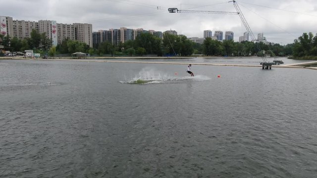 Young man is wakeboarding, performing tricks, backflip, cloudy day