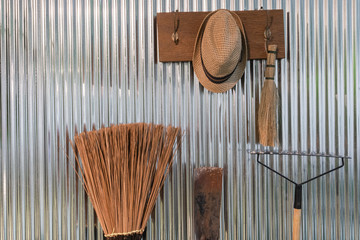 Vintage Straw hat on cloth hanger and equipment for gardening on the zinc wall interior decoration concept