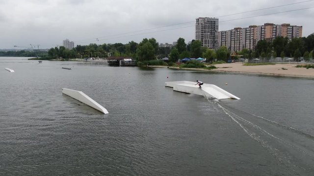 Aerial footage of a man wakeboarding on the big white ramp, tricks and stunts