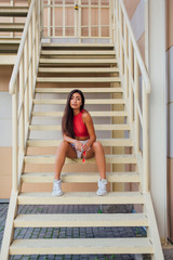Street fashion summer portrait of a women on stairs outdoors.