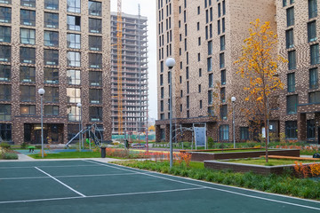 Fototapeta premium business class residential complex with new playgrounds in the yard and construction of new buildings in the background