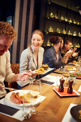 Group of friends sitting in retaurant and eating dinnner.