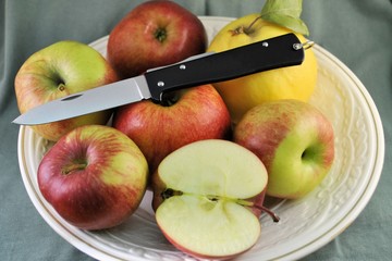 Folding knife stainless steel blade and fresh organic ripe apples quince natural gourmet product dessert