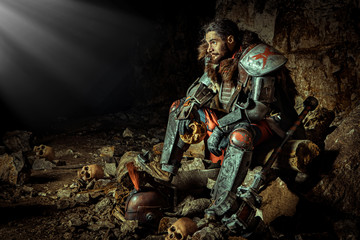 Powerful knight in the armor with the hammer is sitting on the stone. Dungeon on the background.
