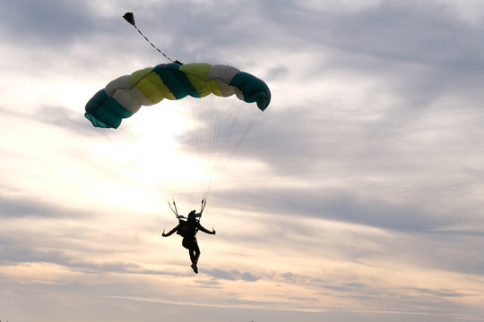 Skydiving. A parachute is in the sunset sky.