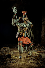 Attack of a powerful knight in the armor with the hammer. Dungeon on the background.