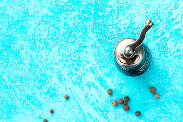 Culinary design template with a place for a recipe or other text, a top shot of a vintage pepper mill with scatterd black peppercorns and copyspace, on a blue texture