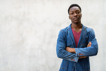 Young handsome African man wearing denim jacket against concrete