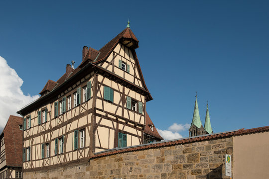Bamberg, Bavaria, Germany - July 14, 2019; Old medieval half-timebered house on a wall, with in the background the towers of Bamberg Cathedral
