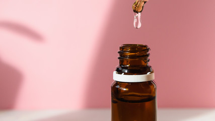 cosmetic product, bottle with hyaluronic acid on a pink background, close-up. Copy space.