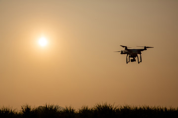 Fototapeta na wymiar Silhouette drone against the background of the sunset. Flying drones in the evening sky. UAV Drone with digital camera. Flying camera take a photo and video.