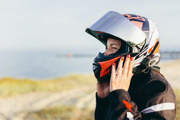 Woman taking off her helmet on a motorbike trip. Break with ocean view