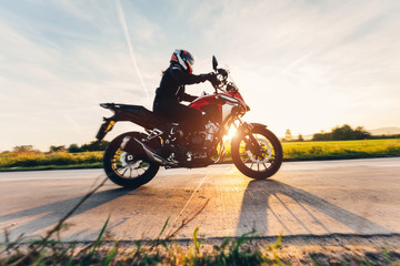 Fototapeta Fast motorcycle drive on asphalt road at sunset. obraz