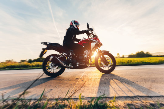 Fast motorcycle drive on asphalt road at sunset.