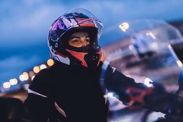 Woman on motorbike in the city at night.