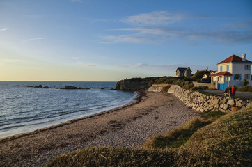 Sunset view on Atlantic shore beach. Path with green grass and long beach