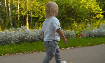 Fototapeta premium Cute toddler walking along the road in the park