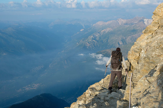 Hiker on the steep and exposed path over the ridge to the summit of Rocciamelone in the Italian Alps
