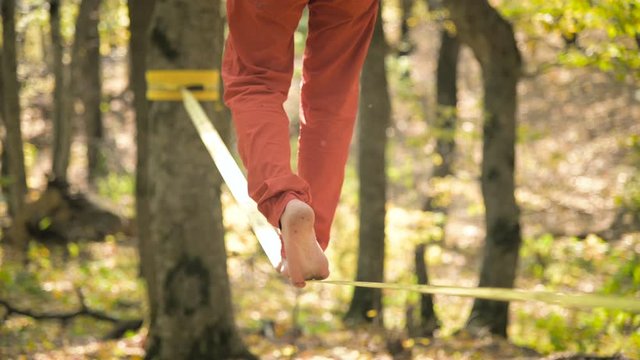 A Slack man aged with a beard in sportswear walks balancing on the slackline. The concept of sports activity at the age of 50. Athlete's foot closeup