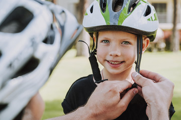 Father helping his daughter to put on bicycle helmet
