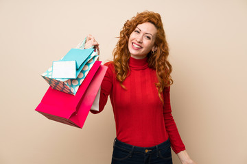 Fototapeta premium Redhead woman with turtleneck sweater holding a lot of shopping bags