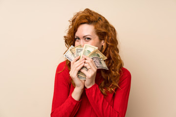 Redhead woman with turtleneck sweater taking a lot of money
