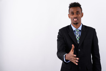 Young bearded African businessman wearing suit against white bac