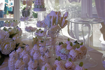 Candy bar: table with a white tablecloth, glassware, cakes, sweets, macaroons, marshmallows, cream, grapes