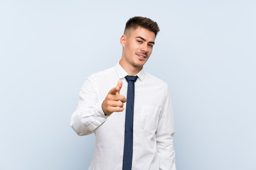 Handsome businessman over isolated blue background points finger at you