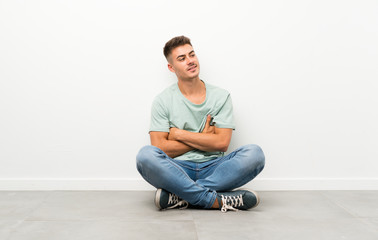 Young handsome man sitting on the floor laughing