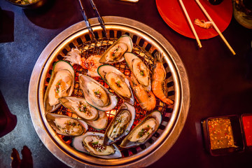 Mussels are on a charcoal stove in a seafood restaurant.