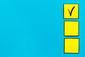 Check mark in yellow check-box on blue background top view copy space