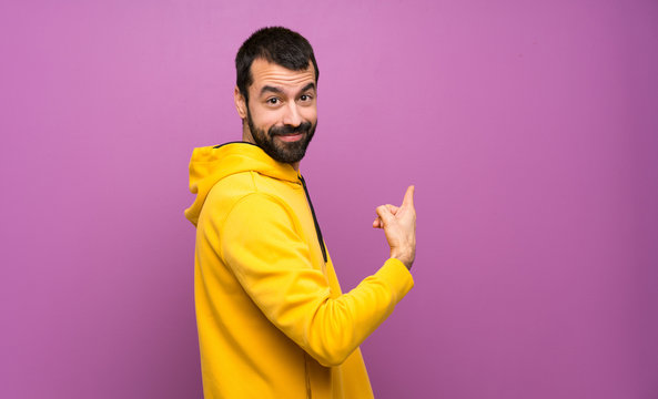Handsome man with yellow sweatshirt pointing back