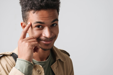 Image of happy african american guy smiling and touching his temple