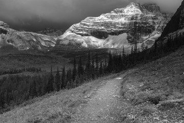 Dramatic view as the early morning sun breaks through the snow heavy clouds of Mt Babel at the back Consolation Lakes, Banff National Park, Canada in black and white