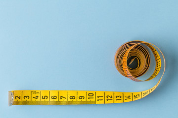 Diet concept. Color measuring tape on blue background.