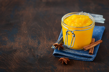 Pumpkin puree, confiture, jam, sauce with spices on a dark wooden table.